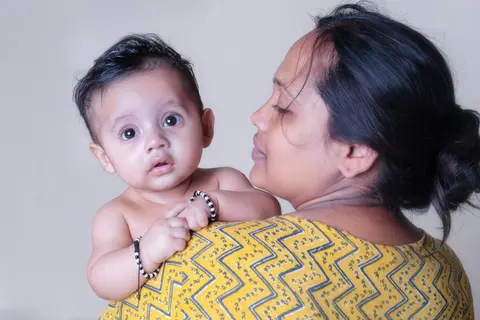 an Indian mother holds her baby close, looking directly at the camera