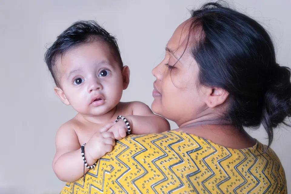 an Indian mother holds her baby close, looking directly at the camera